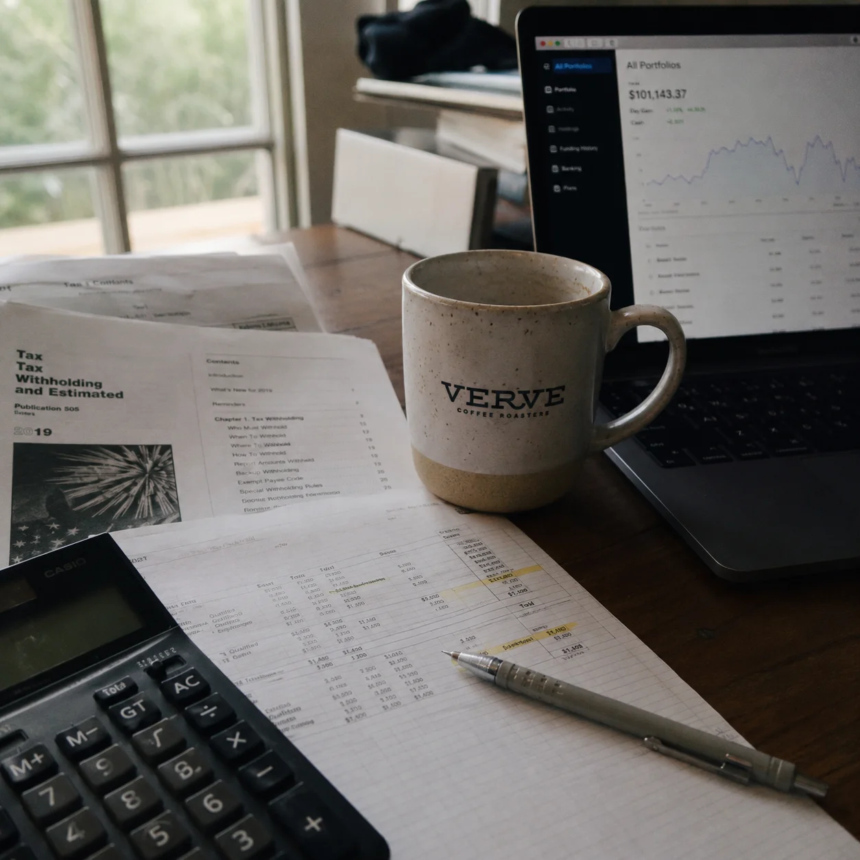 Tax documents and financial planning spreadsheet on a desk with natural side lighting